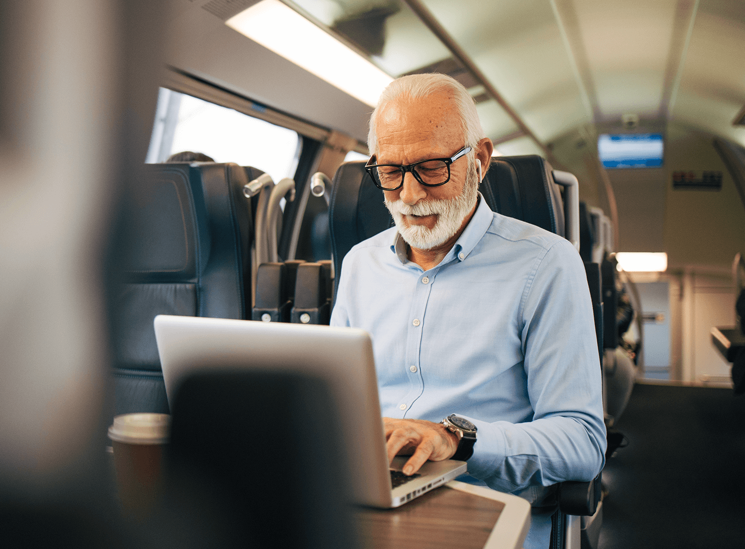 older businessman working on laptop while travelling by train 