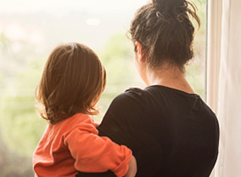 Mom holding young child looking out window image