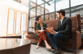 Two businesspeople in conversation on tall brown couch