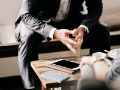 torso-view of suited business man, fingers touching, in meeting