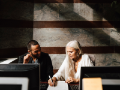 female businesswoman making notes on paper next to diverse young businessman in office