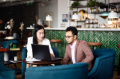 Young business woman with associate looking at laptop screen in cafe