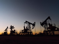 Oil rigs in a field at sunset.