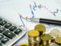 Pens and coins on financial reports or stock market chart analysis, Financial income tax calculation concepts.