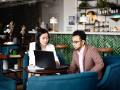 young business woman with associate looking at laptop screen in cafe