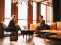 Diverse young professionals talking while sitting by window in office