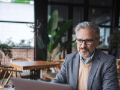 Mature businessman working remotely from cafe using laptop
