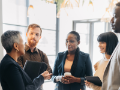 diverse multi-generational men and women standing meeting in office