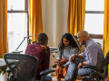 Diverse multi-generational male and female business colleagues meeting with tablet sitting in office