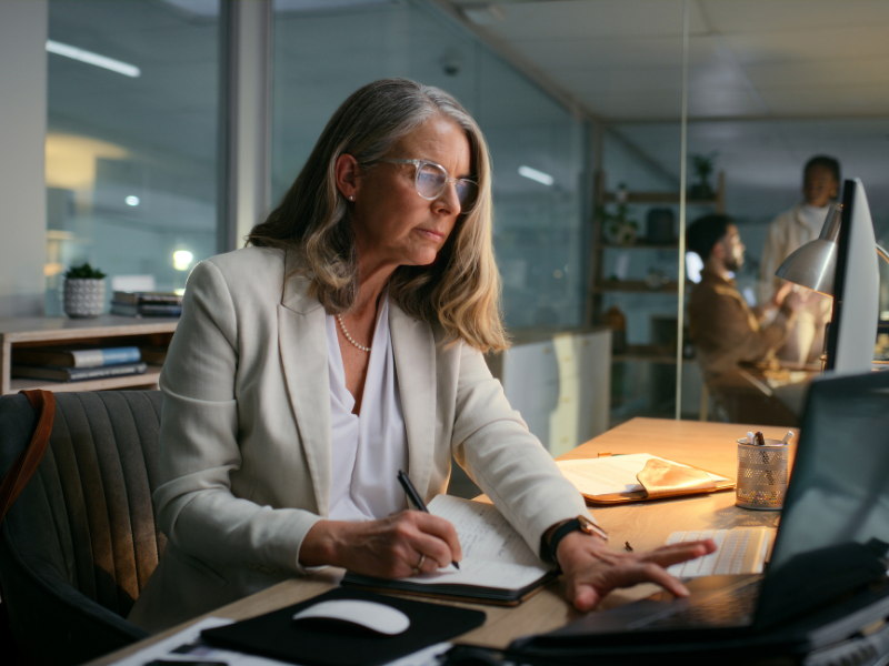 Mature woman with glasses working on laptop in office