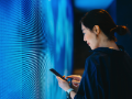 Woman holding phone standing in front of LED screen