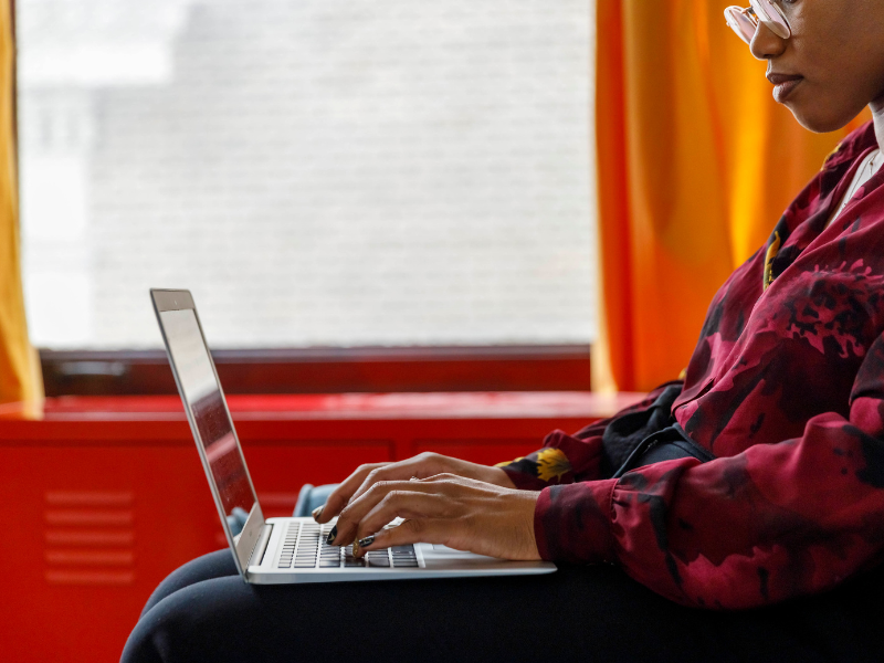 woman typing on laptop in chair
