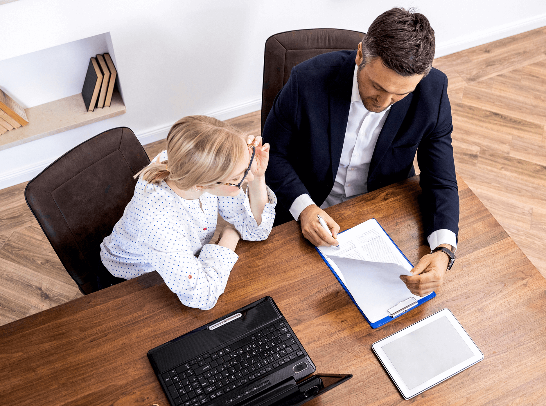 overhead view of seated male and female colleagues reviewing document next to laptop