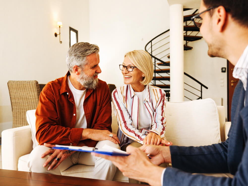 smiling couple on couch discussing trust services with financial advisor
