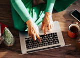 person surrounded by holiday items on laptop