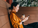 woman outdoors on mobile phone with coffee