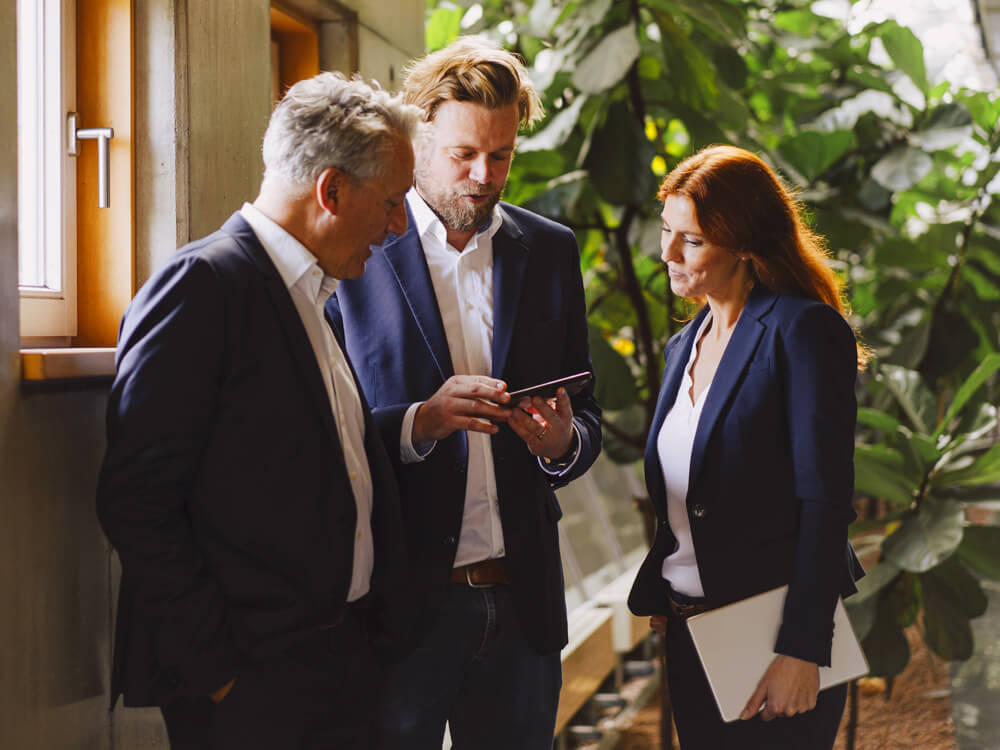 Three financial professionals looking at Cash Sweep information on a tablet.