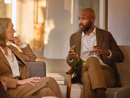 side view of woman seated on couch meeting with a financial advisor
