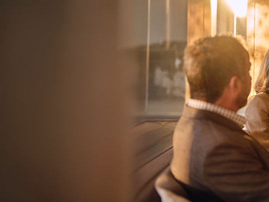 side and back view of man seated on couch meeting with an unseen financial advisor