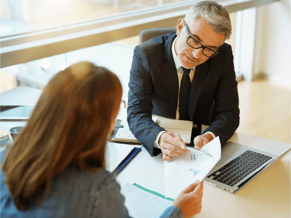 Financial advisor in a meeting with client, studying financial data.