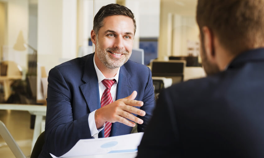 seated financial male financial advisor in office with hand extended