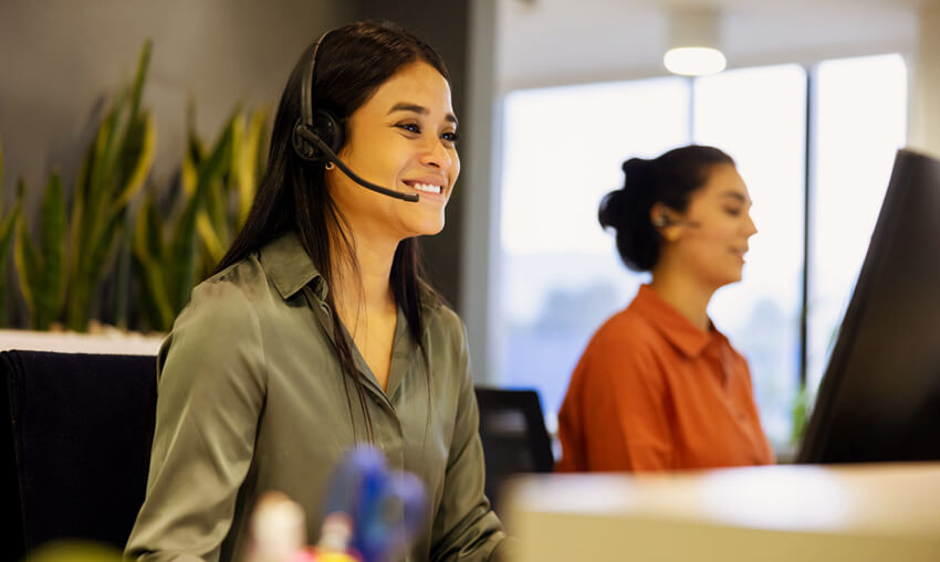 female employee with headset sitting in front of computer monitor