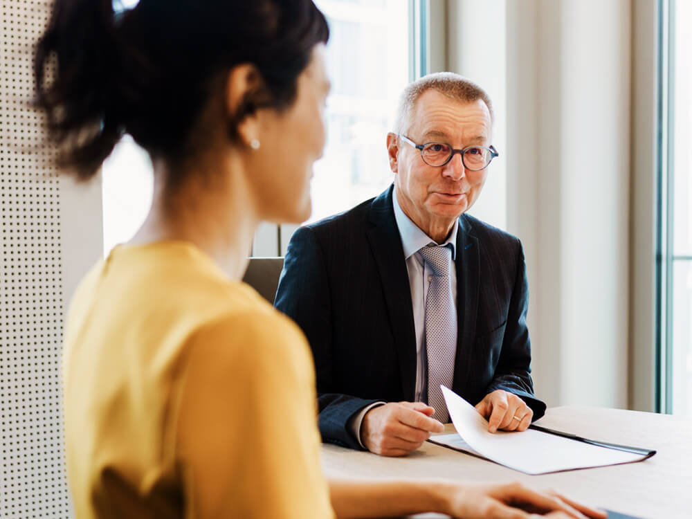 Man and woman in a business meeting at a table in a bright office.