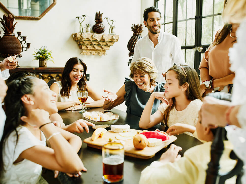 Family gathered around a dining table, smiling and sharing food.