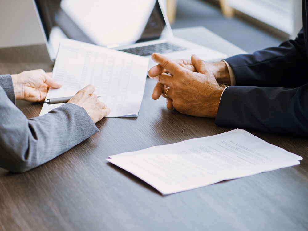 Close-cropped photo of two people reviewing estate planning documents at a desk.