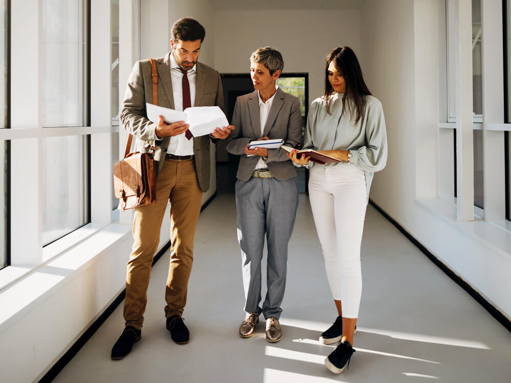 Two businesspeople walking down a windowed hallway