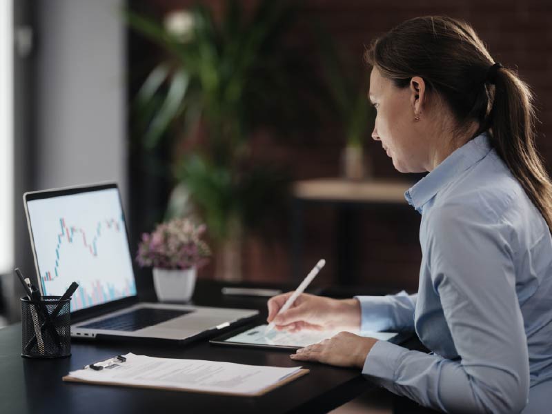 Financial advisor working with both a laptop and a tablet, entering information into the tablet.