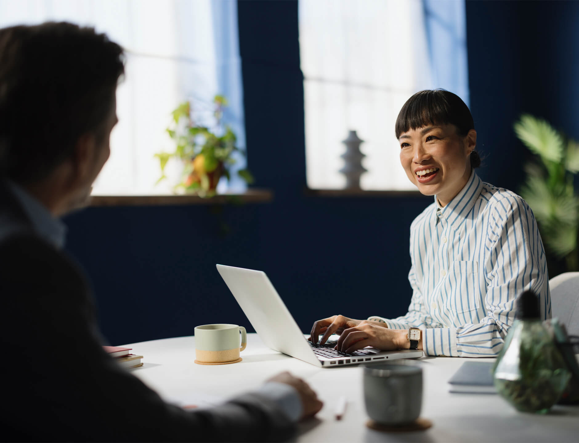 businesswoman with open laptop seated with client at table