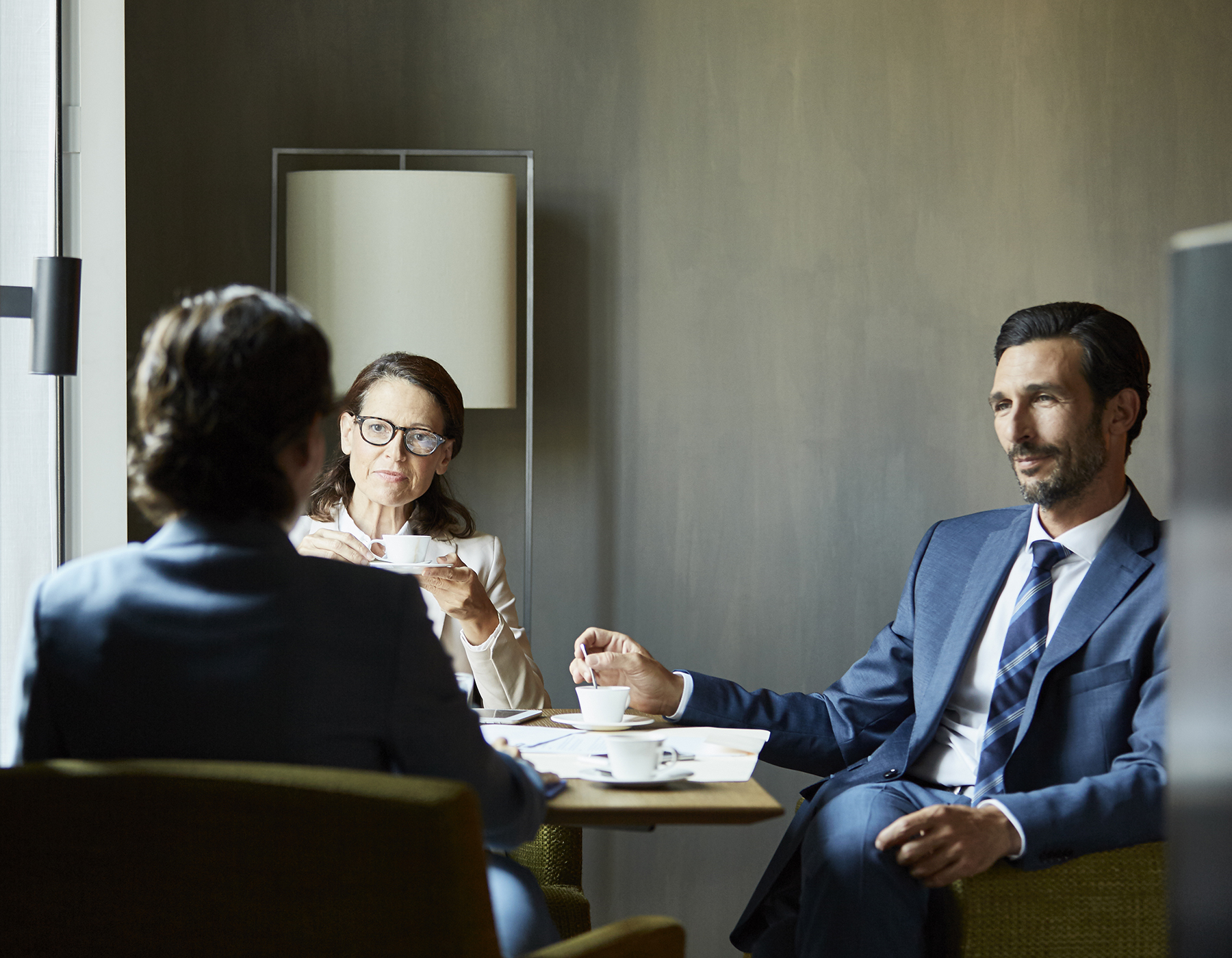 torso-view of suited business man, fingers touching, in meeting