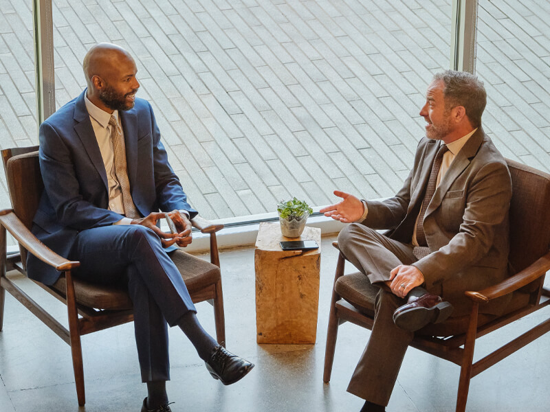 seated financial advisors talking in front of office building window