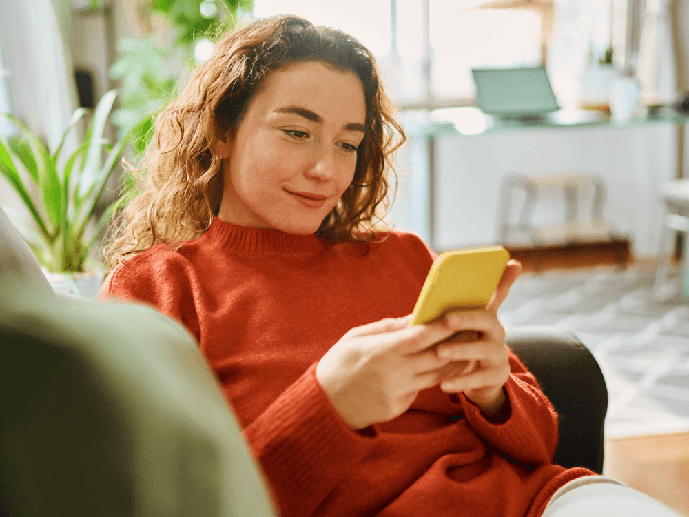 Smiling investor holding and looking at phone looking at financial information.