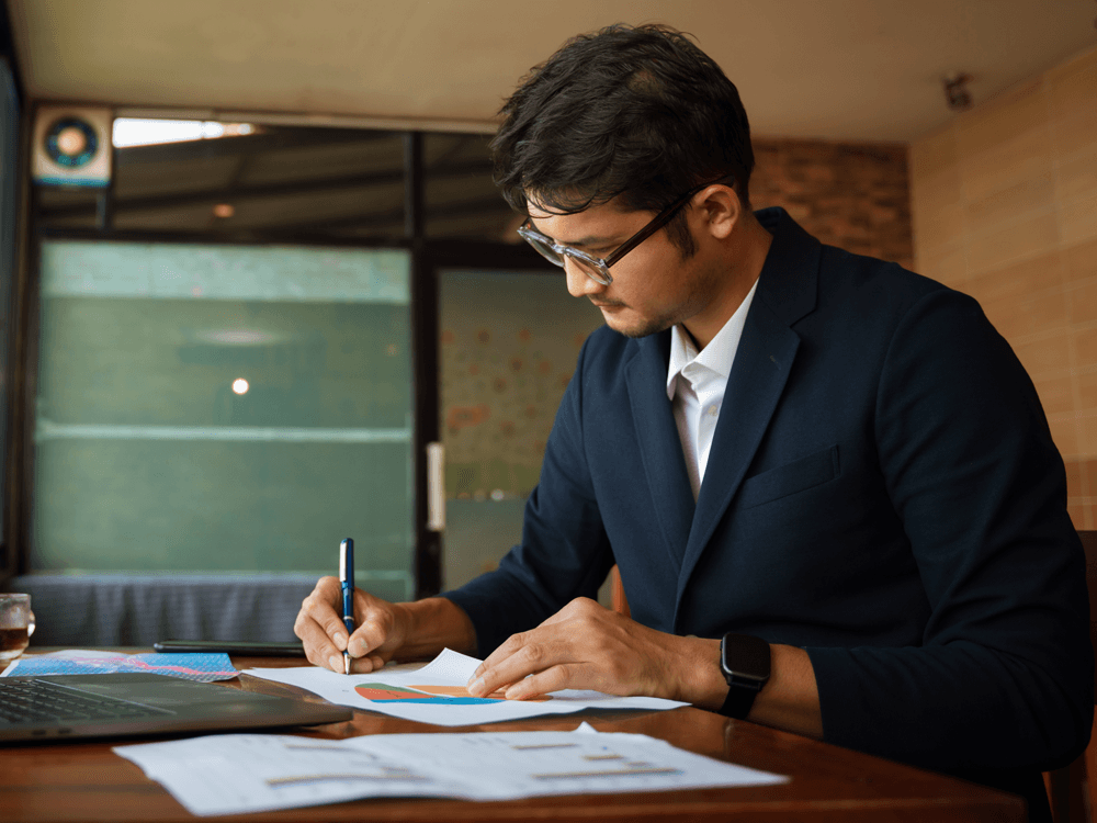 Financial advisor at work with paper charts, annotating the charts.