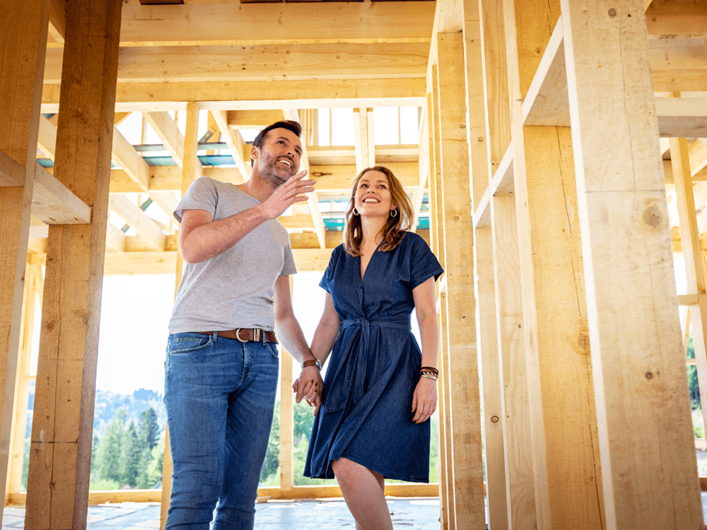 Smiling couple walking through framed house.