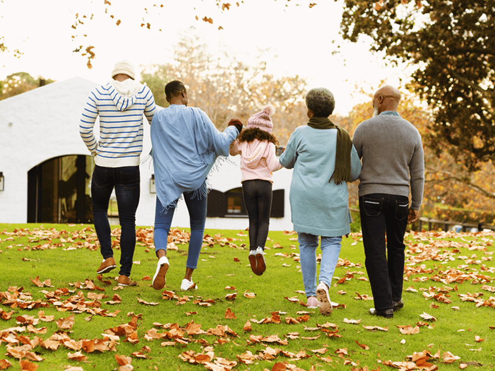 Long shot and rear view of family of five outdoors walking towards home.