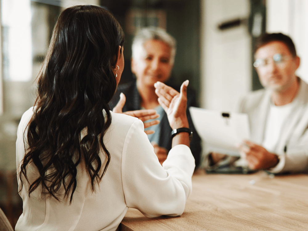 Seated financial advisor in office talking with clients.