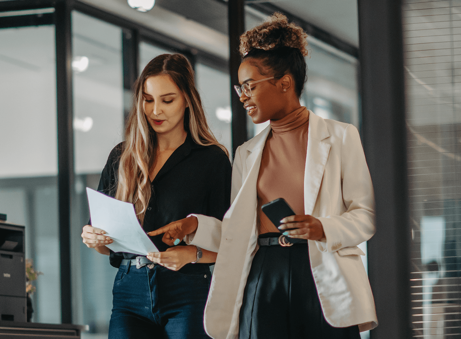 two business colleagues walking in hallway reading letter-size paper