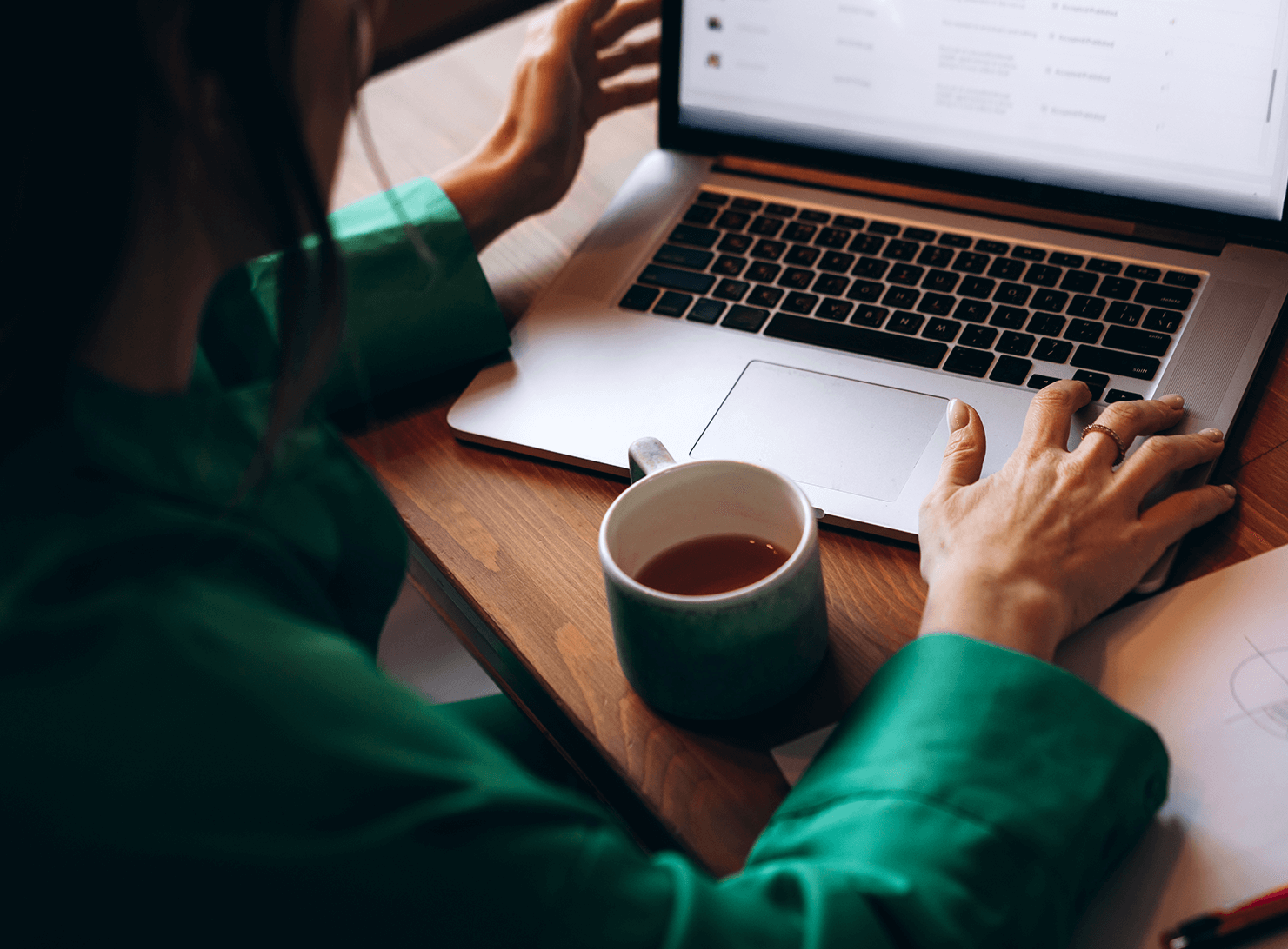 business woman in green top reaching out to laptop