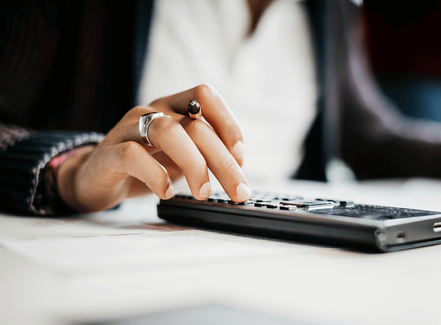 business woman with pencil in hand using small calculator