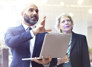 standing man and woman with open lap top in hand image