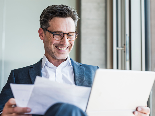 seated business man looking at papers and laptop