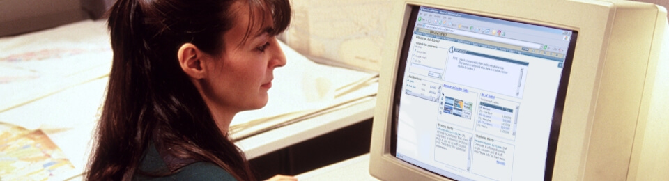 older image of woman seated in front of a monitor with informaton on screen
