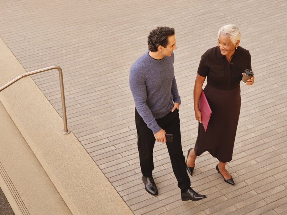 Financial advisors walking outside on bricked plaza with stairs