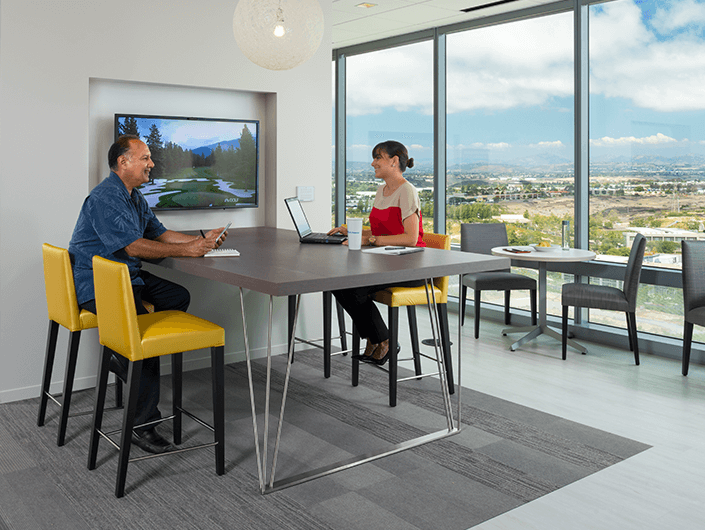 two co-workers sitting at office table in front of window inside LPL corporate office in San Diego
