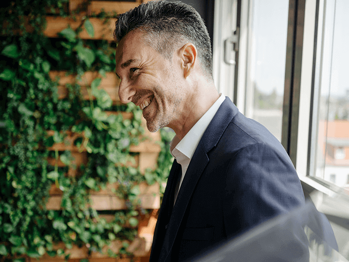 man standing smilin by a window