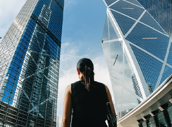 business woman with computer bag standing outside between two tall building 