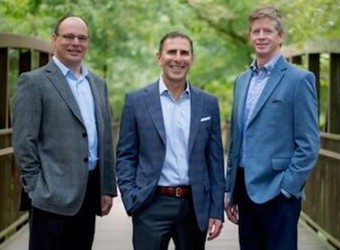 three men in suits standing side by side